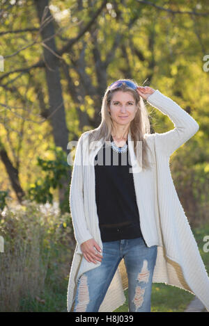 Attraktive blonde junge Frau im Park mit unscharfen Hintergrund Stockfoto