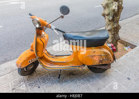 Eine sehr alte orange und schwarz Vespa Super Motorscooter parkt auf einem Bürgersteig in Barcelona, Spanien. Stockfoto