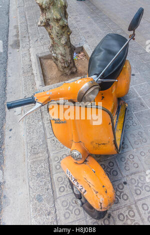 Eine sehr alte orange und schwarz Vespa Super Motorscooter parkt auf einem Bürgersteig in Barcelona, Spanien. Stockfoto