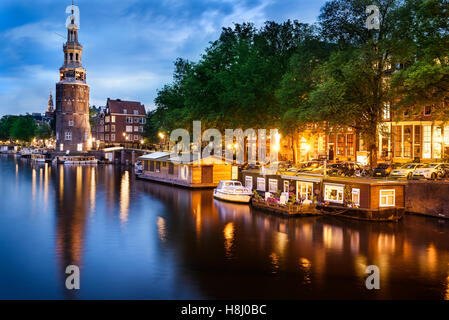 Schöne Nacht in Amsterdam. Nacht Beleuchtung von Gebäuden und Boote in der Nähe der Wasser in den Kanal. Stockfoto