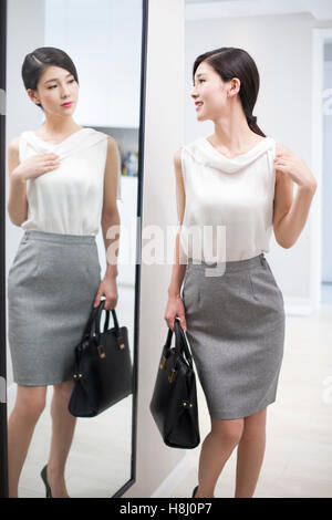 Junge Chinesin, die Prüfung selbst vor Spiegel Stockfoto