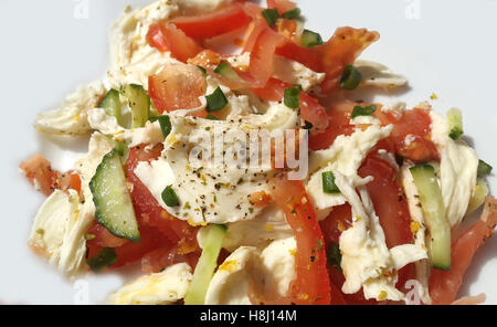 Eine Hochwinkel-Makroaufnahme eines köstlichen gesunden Salats mit Stücken weißem geriebenem Käse, geschnittenen roten Tomaten, knackigen Gurken und grünen Zwiebeln Stockfoto
