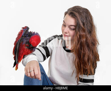 Hübsche Caucsian Teenager-Mädchen mit einem hübschen roten Papagei auf dem arm Stockfoto