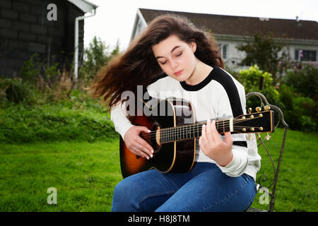 Teenager-Mädchen spielen eine Akustikgitarre außerhalb Stockfoto