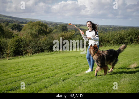 Junge Frau wirft einen Ball für ihren Hund einen deutschen Schäferhund. Stockfoto