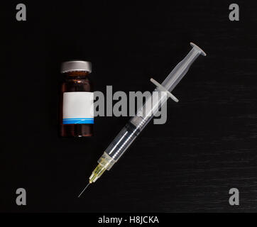 Spritze und Flasche auf schwarzem Hintergrund isoliert. Stockfoto
