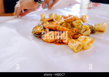 Krustentier Meeresfrüchte mit Muscheln, Austern und Garnelen am Tisch und weiß Wachspapier, Tiefenschärfe, Essen Hintergrund. Stockfoto