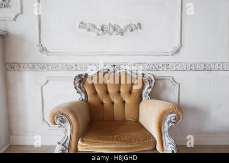 Wohnzimmer mit antiken stilvolle Beige Sessel auf Luxus weiße Wand Basrelief Stuck Zierleisten-Jahrgang Designelemente Stockfoto