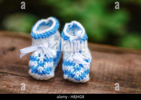 Blaue Hand gemacht häkeln Babyschuhe auf hölzernen Hintergrund, Nahaufnahme Stockfoto