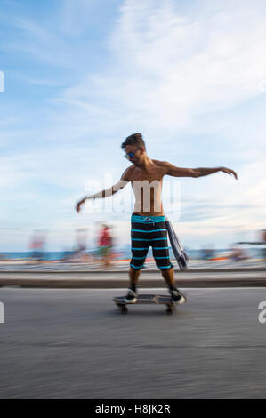 RIO DE JANEIRO - 6. März 2016: Junge Carioca Brasilianer auf Skateboard bewegt sich in eine Bewegungsunschärfe entlang der Ipanema-Strand. Stockfoto