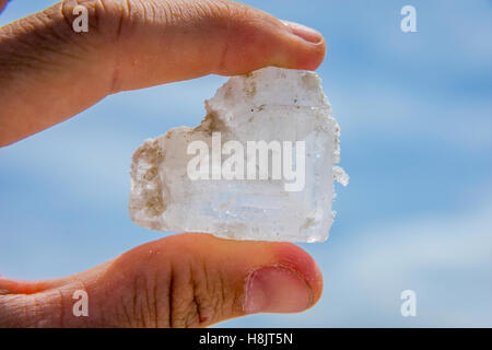 Halten große Salzkristall in der hand gegen blauen Himmel Stockfoto