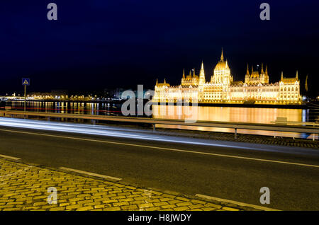 Nachtleben in Budapest mit dem Auto wegen und beleuchtete Parlamentsgebäude im Hintergrund Stockfoto