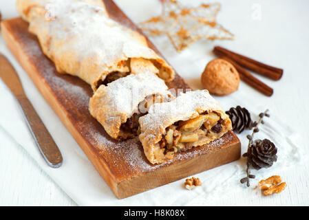 Weihnachten selbstgemachter Kuchen. Apfelstrudel (Pie) mit Rosinen, Walnüssen und Puderzucker mit Weihnachts-Dekor hautnah. Stockfoto