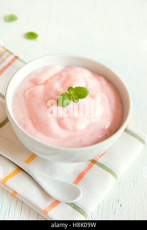 Erdbeer-Joghurt mit Minze auf hölzernen weißen Hintergrund. Erdbeer Joghurt. Rosa Joghurt. Stockfoto