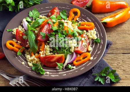 Frische Bio Tomaten-Couscous-Salat mit Gemüse und grünen - gesunde vegetarische Salate auf rustikale Platte hautnah Stockfoto