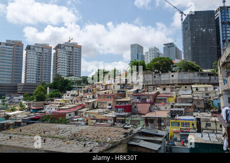 Bunte Häuser für die armen Bewohner von Luanda, Angola. Diese Ghettos stehen in starkem Kontrast zu den modernen reichen Hochhäusern im Hintergrund Stockfoto