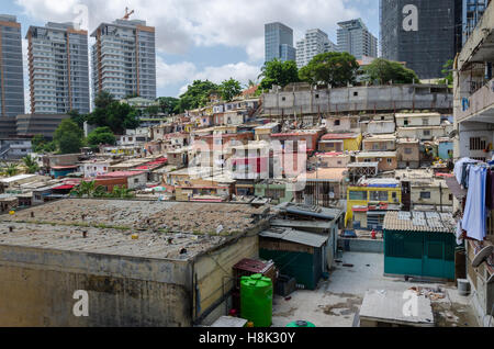 Bunte Häuser für die armen Bewohner von Luanda, Angola. Diese Ghettos stehen in starkem Kontrast zu den modernen reichen Hochhäusern im Hintergrund Stockfoto
