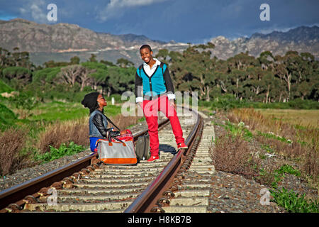 afrikanischer Mann und ein Mädchen warten auf Zug auf den Gleisen Stockfoto