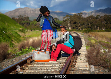 afrikanischer Mann und ein Mädchen warten auf Zug auf den Gleisen Stockfoto