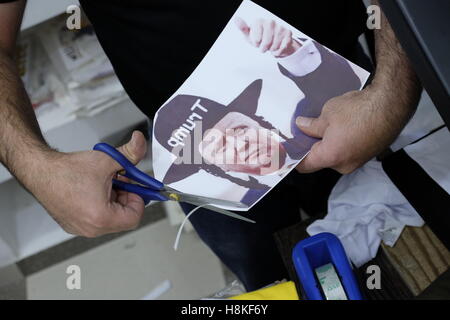 Jerusalem, Israel. 13. NOVEMBER 2016. Ein palästinensischer Mann schneiden, ein Papier mit neu gewählten gekleidet, US Präsident Donald Trump um ultra-orthodoxer Jude aussehen, um ein T-shirt mit diesem Bild an einen Souvenir-Shop in der Altstadt Ost-Jerusalem, Israel am 13. November 2016 vorzubereiten. Stockfoto