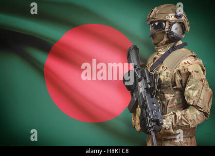 Soldat im Helm holding Maschinengewehr mit Nationalflagge auf Hintergrund - Bangladesch Stockfoto