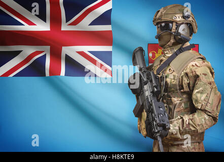 Soldat im Helm holding Maschinengewehr mit Nationalflagge auf Hintergrund - Fidschi Stockfoto