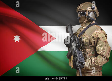 Soldat im Helm holding Maschinengewehr mit Nationalflagge auf Hintergrund - Jordanien Stockfoto