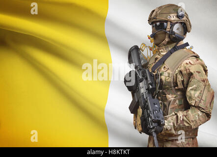 Soldat im Helm holding Maschinengewehr mit Nationalflagge auf Hintergrund - Staat Vatikanstadt Stockfoto