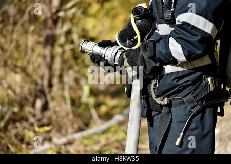 Feuerwehrmann mit Hochdruck-Wasserschlauch Löschen eines Brandes Stockfoto