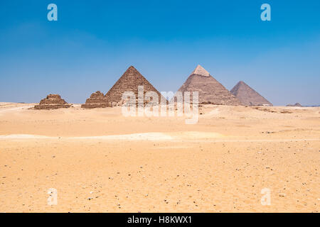 Kairo, Ägypten riesigen Sahara-Wüste mit den drei großen Pyramiden von Gizeh im Hintergrund vor einem strahlend blauen Himmel. Von links nach r Stockfoto