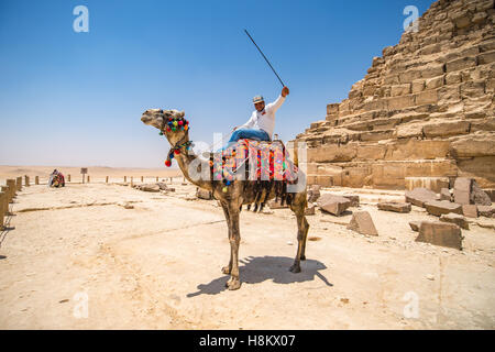 Kairo, Ägypten Kamel und seines Fahrers ruht in der Wüste neben Rubel am Fuße eines der großen Pyramiden von Giza. Stockfoto