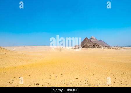 Kairo, Ägypten riesigen Sahara-Wüste mit den drei großen Pyramiden von Gizeh im Hintergrund vor einem strahlend blauen Himmel. Von links nach r Stockfoto