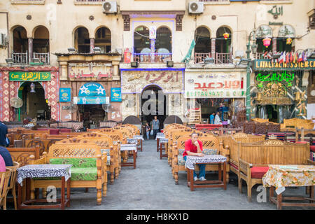 Kairo, Ägypten. Mann sitzt allein in einem Sitzbereich umgeben von verschiedenen Ladenschilder im Outdoor-Basar / Flohmarkt Khan el- Stockfoto