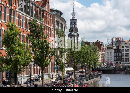 Amsterdam, Niederlande Blick der Touristen zu Fuß entlang eines Amsterdamer Kanals. Im Hintergrund ist Munt Tower zusammen mit Stockfoto