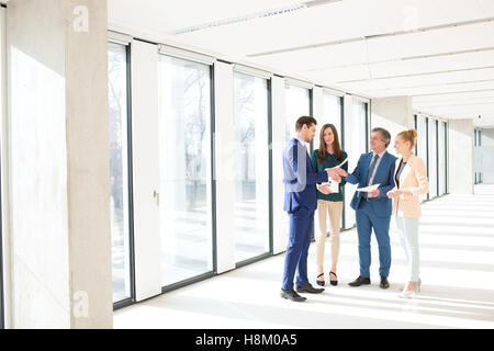 Volle Länge des Business-Menschen-Diskussion über Dokumente im leeren Büro Stockfoto