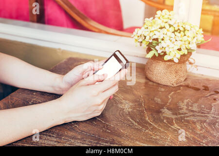 Hand-Frau mit Telefon im Coffee-Shop mit Vintage getönten hautnah. Stockfoto