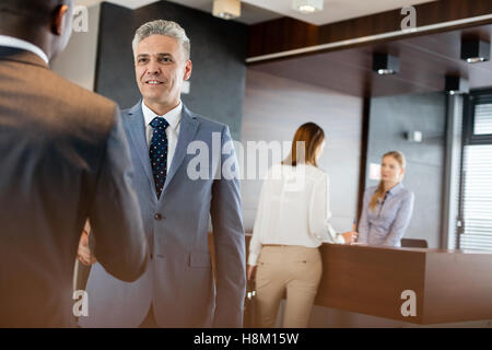Reife Geschäftsmann Händeschütteln mit männlichen Kollegen im Büro Stockfoto