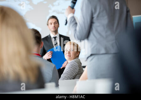 Lächelnd Geschäftsfrau sucht Kollegen sprechen während seminar Stockfoto