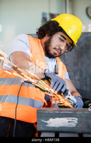 Junge Arbeiter in Schutzkleidung Schleifen von Metall in der Industrie Stockfoto