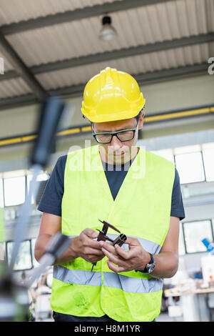 Mitte Erwachsenen Arbeiter Messung Metall mit Bremssattel in der Industrie Stockfoto