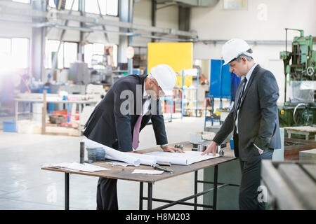 Geschäftsleute, die Blaupause an Werkbank in der Metallbranche zu prüfen Stockfoto