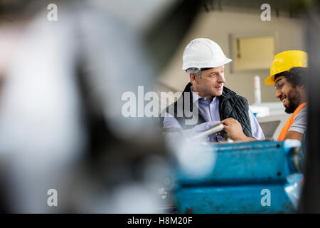 Reifen männlichen Vorgesetzten im Gespräch mit-Arbeiter in der Metallindustrie Stockfoto