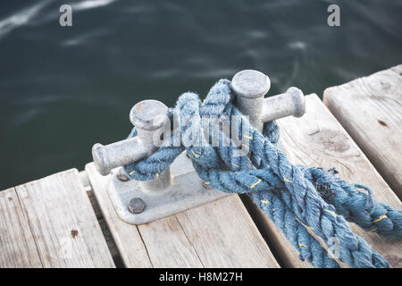 Poller mit gebundenen blaues Seil montiert auf weißen Holzmole Liegeplatz, yacht Marina Sicherheitsausrüstung Stockfoto