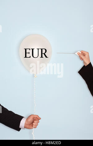 Abgeschnittenen Hände halten Nadel und knallende Ballons mit Text Euro Stockfoto