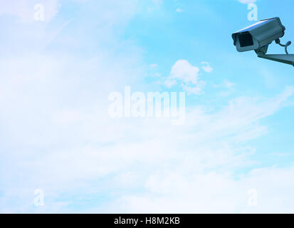 Überwachungskamera an Wand gegen Wolken Stockfoto