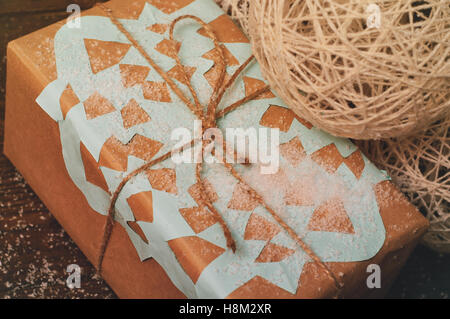 Weihnachts-Geschenk liegt auf einem Holztisch, verpackt in Kraftpapier mit einer blaue Schneeflocke Stockfoto