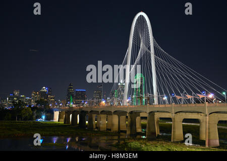 Die Margaret Hunt Hill Bridge ist nachts beleuchtet und bietet spektakuläre Aussicht auf die Skyline von Dallas. Stockfoto