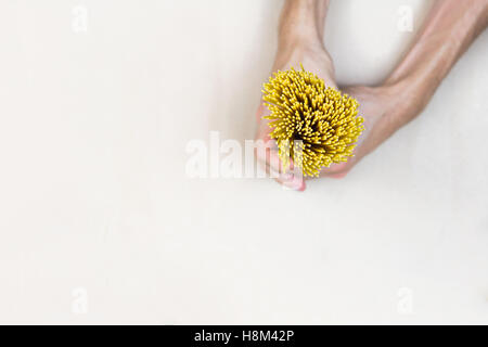 Rohe Spaghetti in Händen. Draufsicht Bündel von ungekochten Spaghetti in männlichen Händen auf leichte Kraftpapier Stockfoto