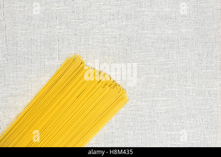 Rohe Spaghetti flach zu legen. Reihe von ungekochten Spaghetti Draufsicht auf leichte weiße Leinwand Stockfoto