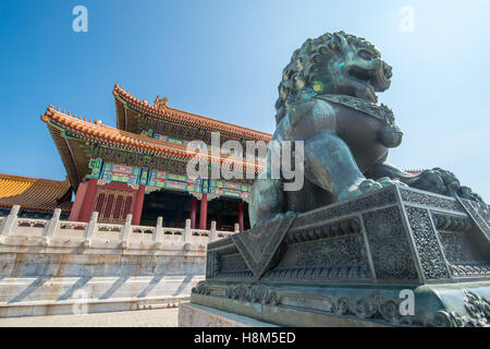 Peking - Detail einer bronzenen Wächter Löwe Statue (Shi) mit der verzierten Architektur des Palastmuseums in der backg Stockfoto